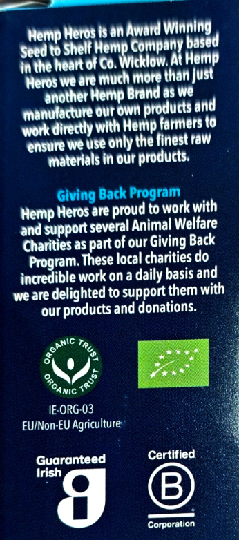 Back of a dark blue Hemp Heroes seed packet showing company text, the Giving Back Program, organic trust logos, and certification marks including Irish Guaranteed and Certified B Corporation.