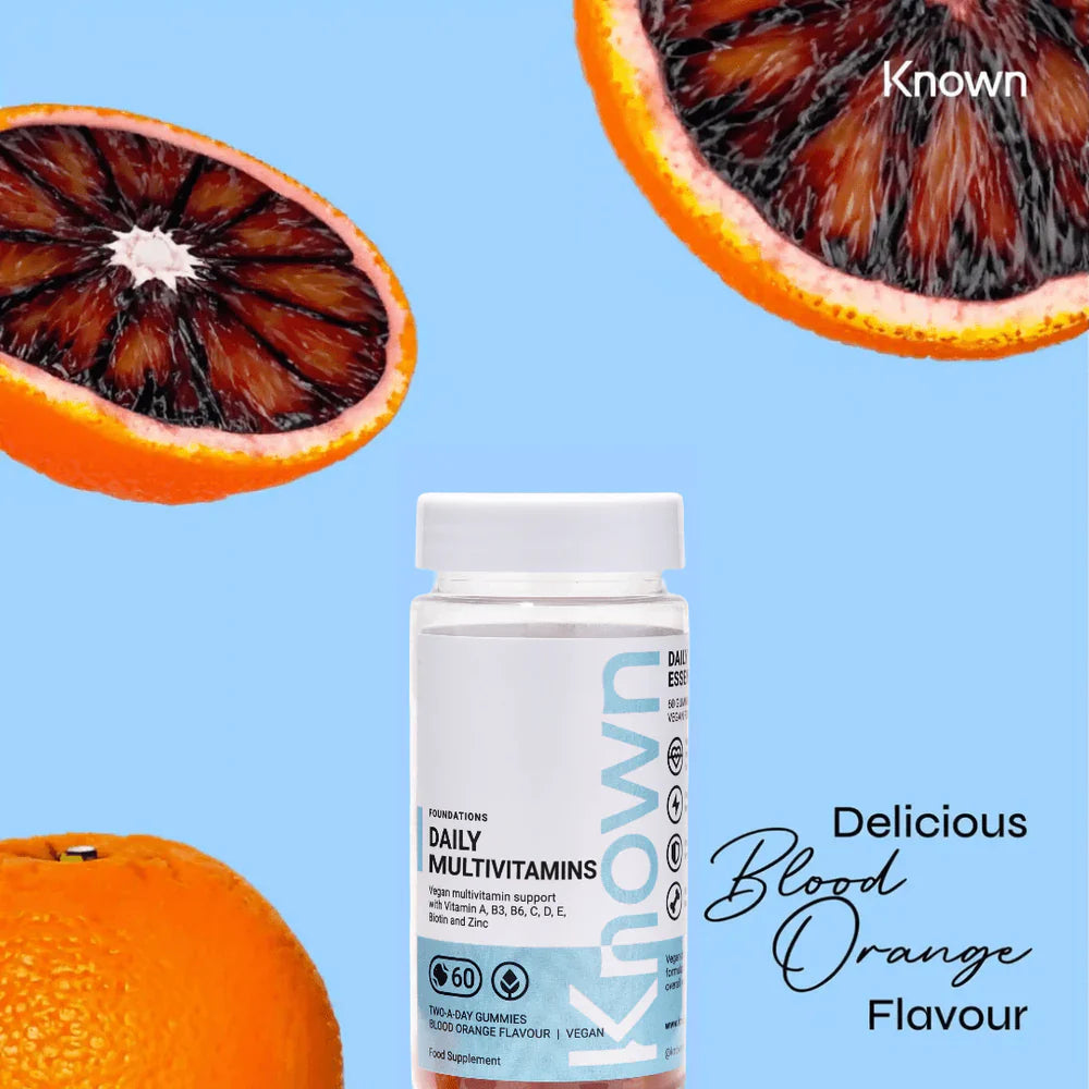 "Known Daily Multivitamin Gummies VEGAN bottle surrounded by fresh blood oranges, emphasizing the delicious natural flavor."