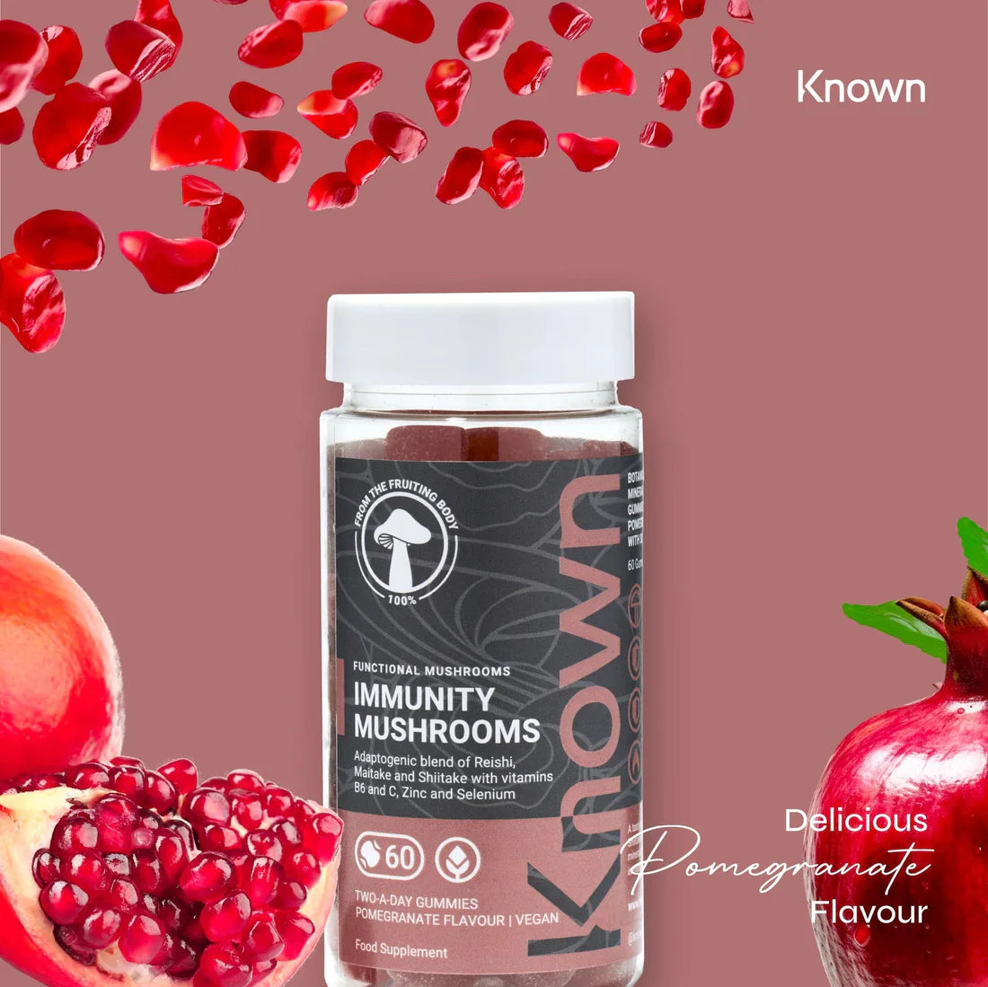 "Known Immunity Mushrooms Gummies VEGAN bottle surrounded by fresh pomegranate, showcasing the delicious natural flavor."