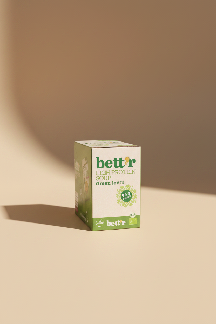 A box of bettr High Protein Soup Green Lentil, showing the green and white packaging with product details, set against a slightly blurred background of other grocery items.
