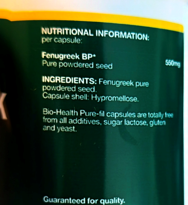 Close-up of a supplement bottle label showing nutritional information for Fenugreek BP, including ingredients and capsule details, with a dark green background and yellow band at the top.