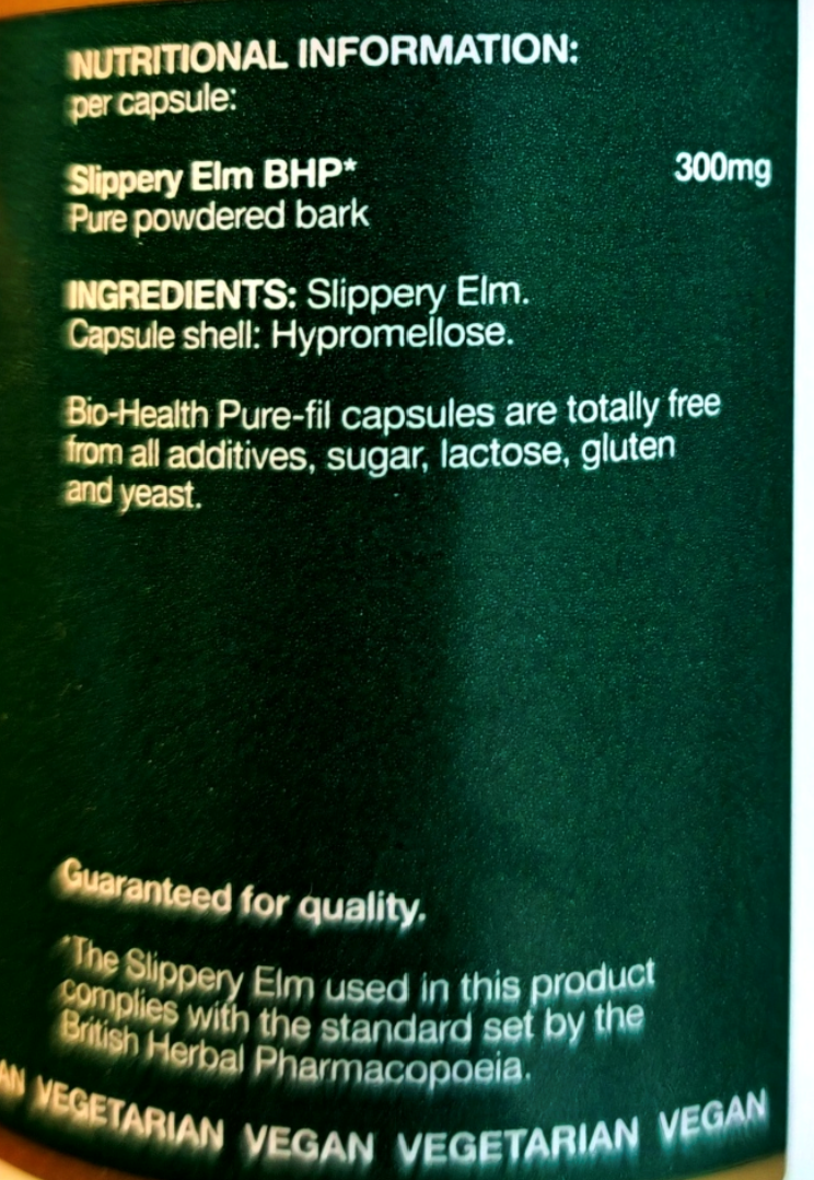 Close-up of a dark green supplement label showing nutritional information and ingredients for Slippery Elm BHP, including text about pure powdered bark and Hypromelose capsule shell.