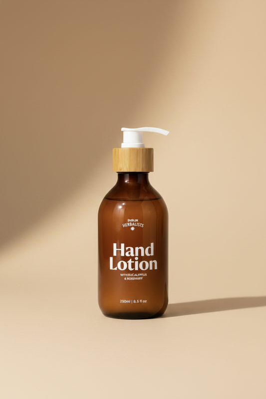 An amber glass pump bottle of Dublin Herbalists Hand Lotion with a bamboo cap and white pump, on a white background.