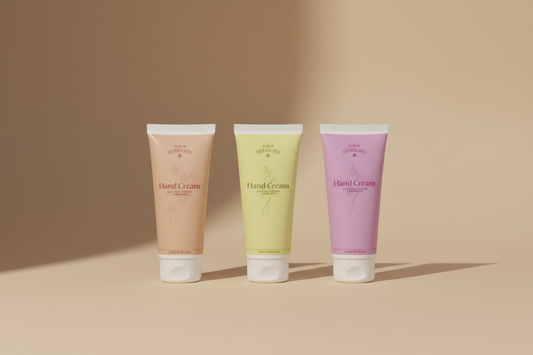 Three squeeze tubes of Dublin Herbalists Hand Cream in peach, pale yellow, and lavender pink, arranged side by side against a light beige background.