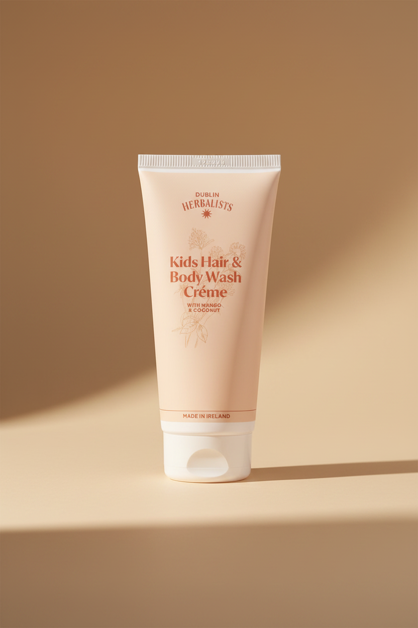 A tube of Dublin Herbalists Kids Hair & Body Wash Crème, featuring a pale peach-pink body with coral-red text and botanical illustrations, set against a clean white background.