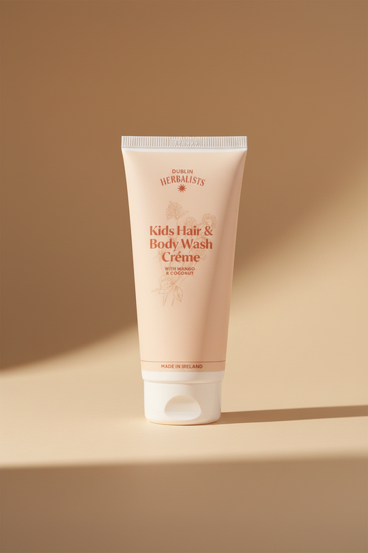 A tube of Dublin Herbalists Kids Hair & Body Wash Crème, featuring a pale peach-pink body with coral-red text and botanical illustrations, set against a clean white background.