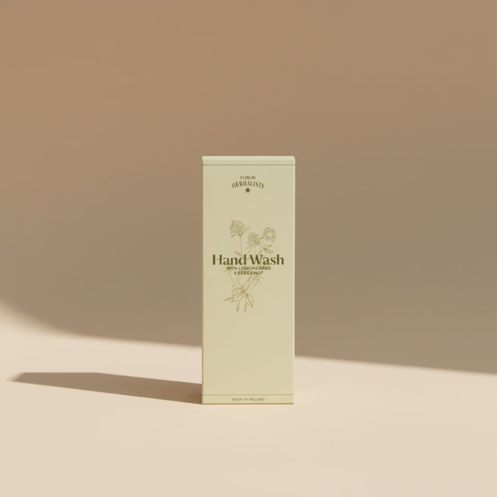 A cream-colored box of Dublin Herbalists Hand Wash with Lemongrass & Bergamot, featuring botanical line drawings and product text, photographed in a casual setting.