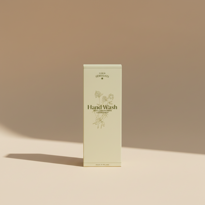 A cream-colored box of Dublin Herbalists Hand Wash with Lemongrass & Bergamot, featuring botanical line drawings and product text, photographed in a casual setting.