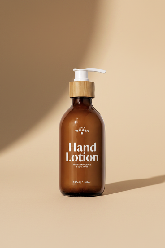 An amber glass pump bottle of Dublin Herbalists Hand Lotion with a bamboo-look cap and white pump, on a light gray background.
