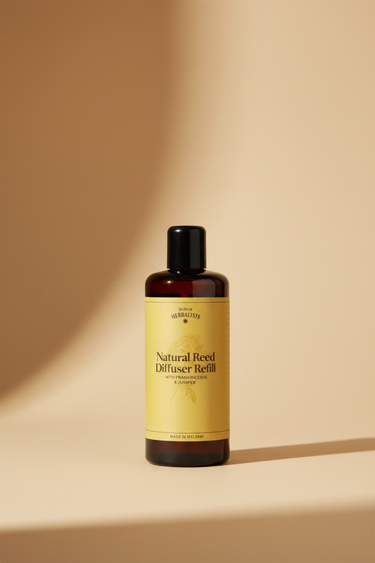 A bottle of Dublin Herbalists Natural Reed Diffuser Refill with Frankincense & Juniper, featuring a black bottle and cap with a yellow label.