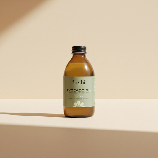 A bottle of Fushi Avocado Oil, showing the amber glass bottle and a light sage green label with black text, on a white background.