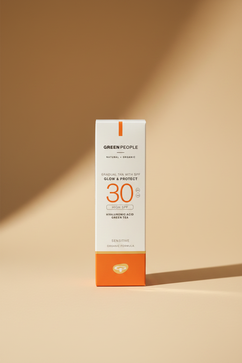 A hand holding a box of Green People Glow & Protect SPF 30 Gradual Tan sunscreen. The packaging is white with orange accents and a gold band near the bottom.