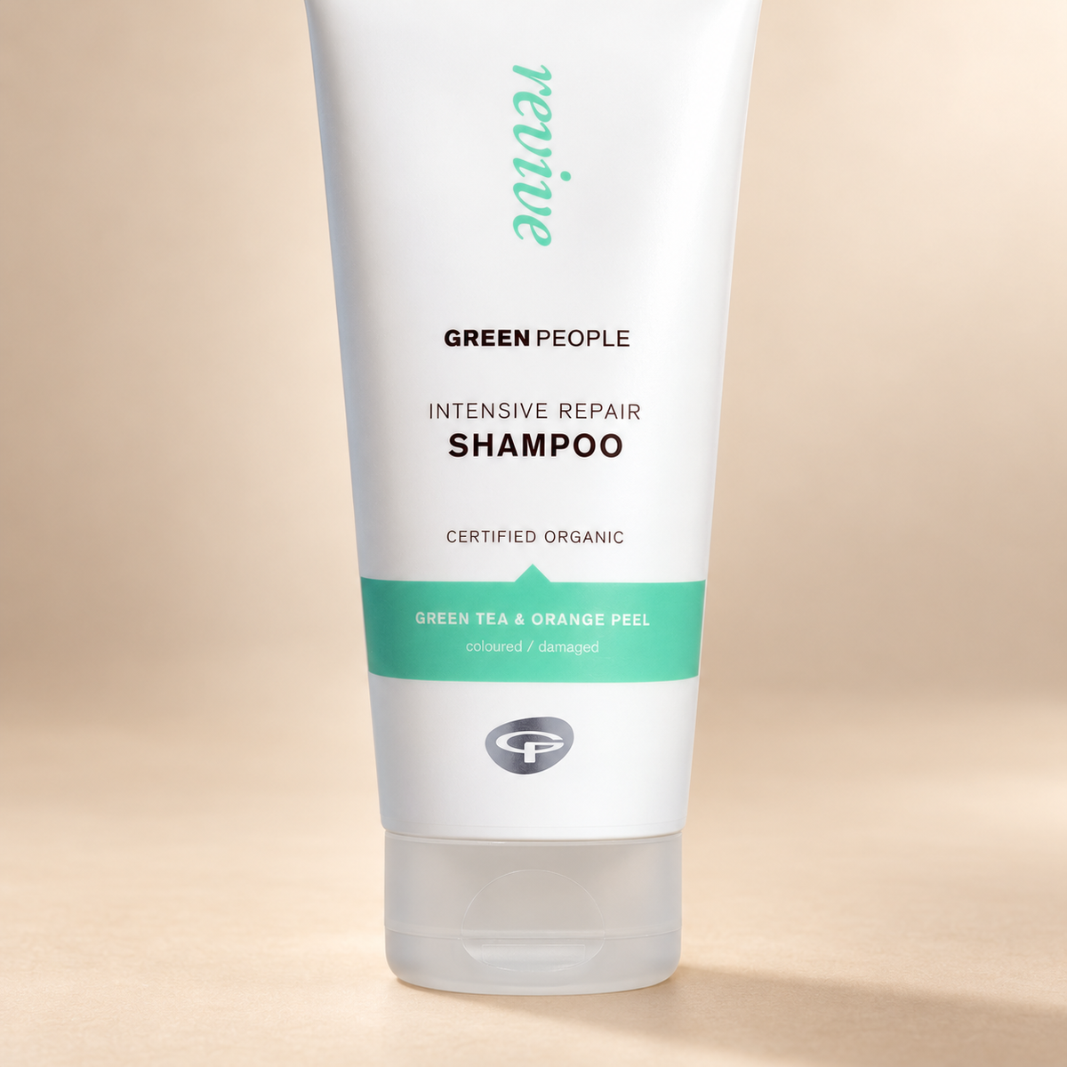 Close-up of Green People Intensive Repair Shampoo label, green tea and orange peel band, and cap