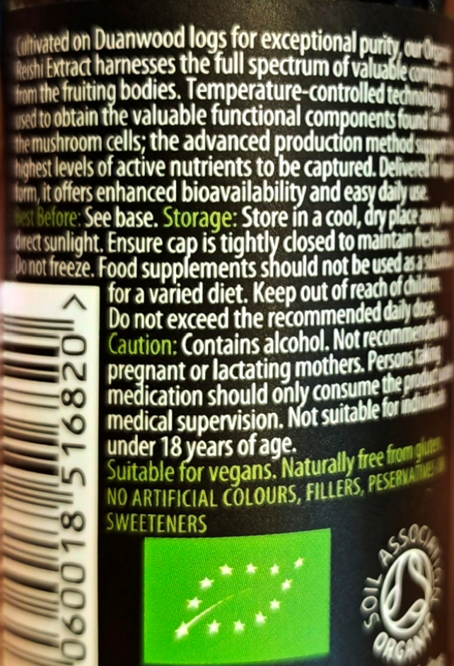 Close-up of a supplement label showing white text on a dark background with storage, caution, and suitability information, plus a green organic-style logo and a barcode.