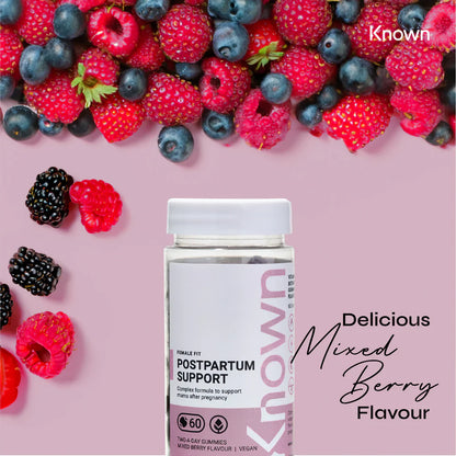 "Known Postpartum Support Gummies VEGAN bottle surrounded by fresh mixed berries, emphasizing the delicious natural flavor."