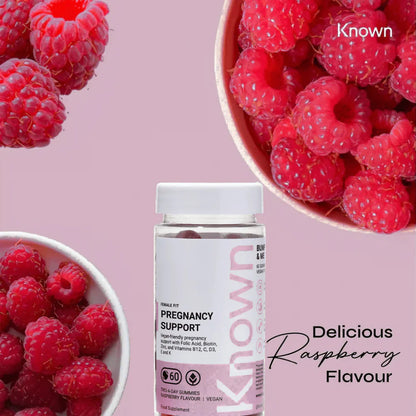 "Known Pregnancy Support Gummies VEGAN bottle next to bowls of fresh raspberries, emphasizing the delicious raspberry flavor."