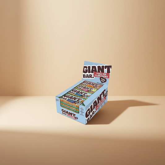 A light blue Giant Bar snack display box filled with multiple wrapped bars, shown on a plain white studio background. The box prominently reads 'GIANT BAR' and 'FULL-ON FLAPJACKS,' with flavor labels visible on the bars inside.