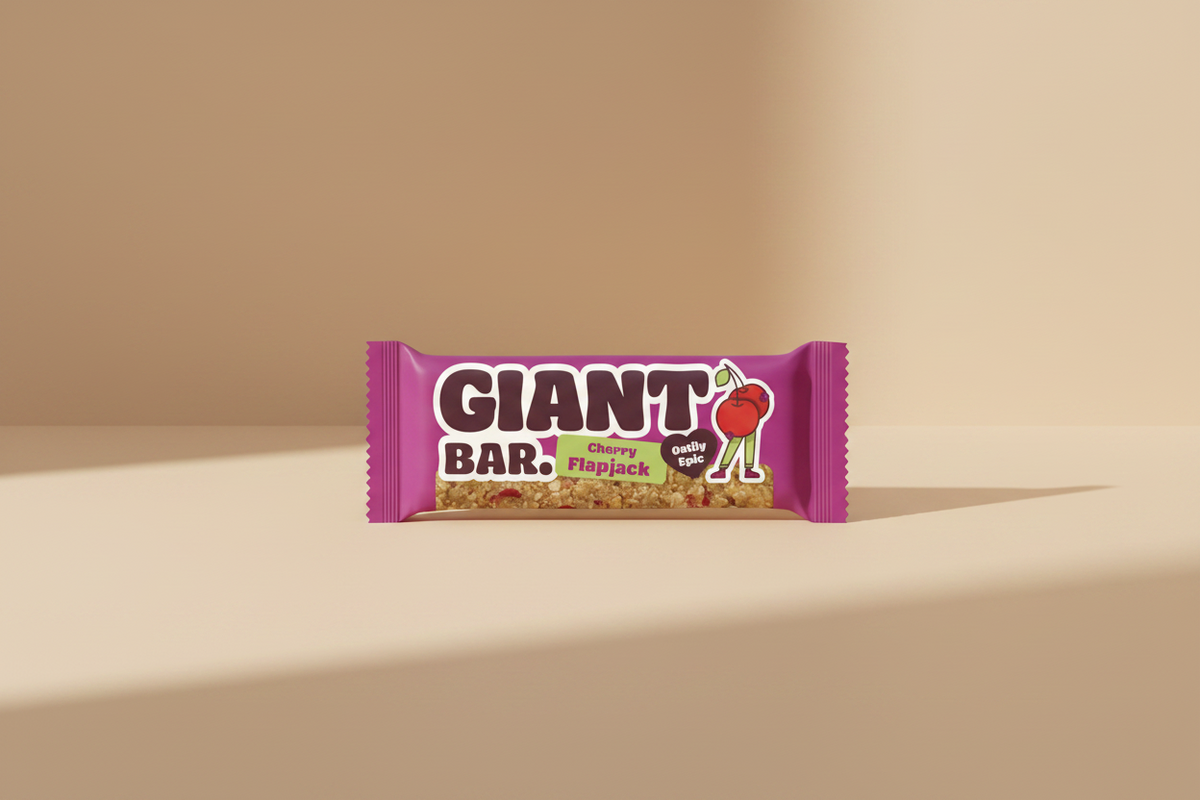 A packaged Giant Bar Cherry Flapjack oatmeal snack bar in a bright magenta wrapper, shown against a solid light green background.