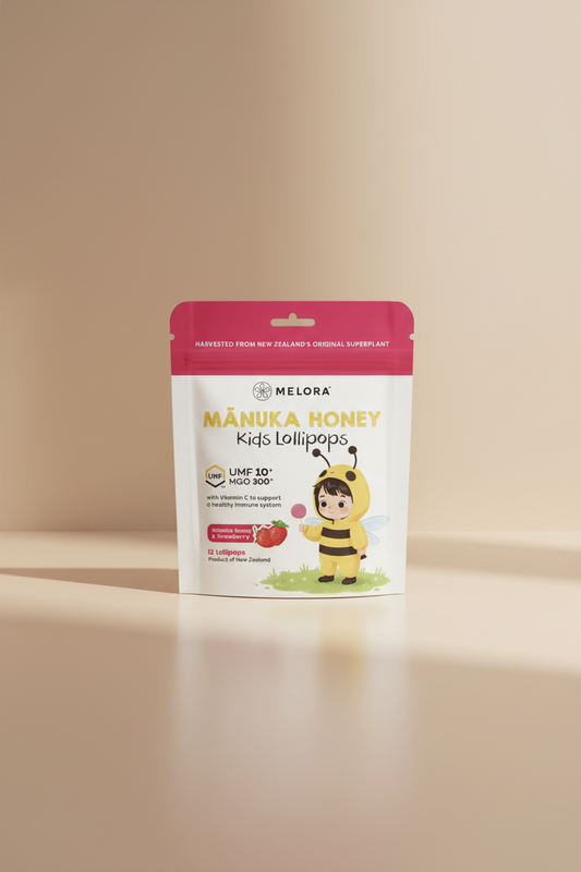 Melora Mânuka Honey Kids Lollipops in a stand-up pouch package. The packaging features a white and pink design with a cartoon bee holding a lollipop and a strawberry graphic indicating the Mânuka Honey & Strawberry flavor.