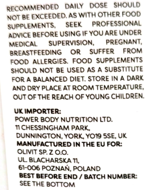 Close-up of a white supplement package showing black printed warning and manufacturer information text.