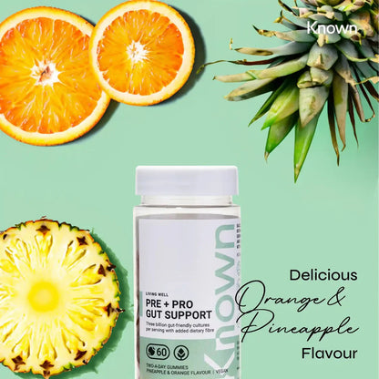 "Known Pre+Pro Gut Support Gummies VEGAN bottle surrounded by pineapple and orange slices, emphasizing the delicious tropical flavor."