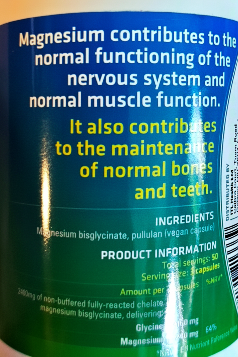 Close-up of the back label of a magnesium supplement bottle, showing text about magnesium benefits, ingredients, and product information on a blue-to-green gradient background.