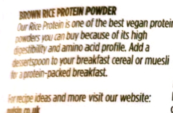 Close-up of a brown printed label on a white package, showing text about brown rice protein powder and website contact information.