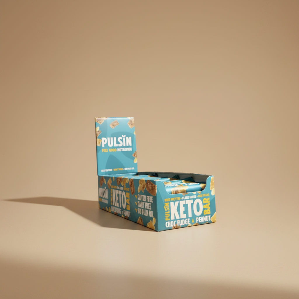 Box of Pulsin' Keto Choc Fudge Peanut bars held by a hand against a gray background