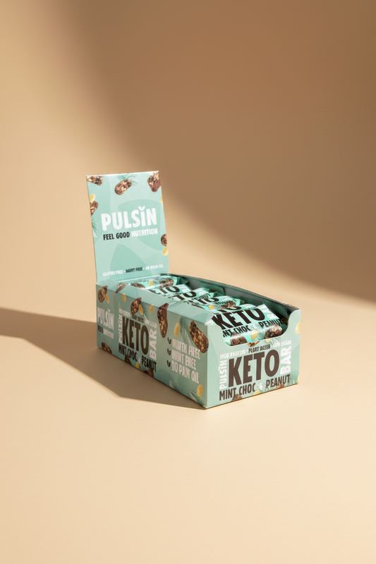 Box of Pulsin' Keto Mint Choc Peanut bars held by a hand on a gray background