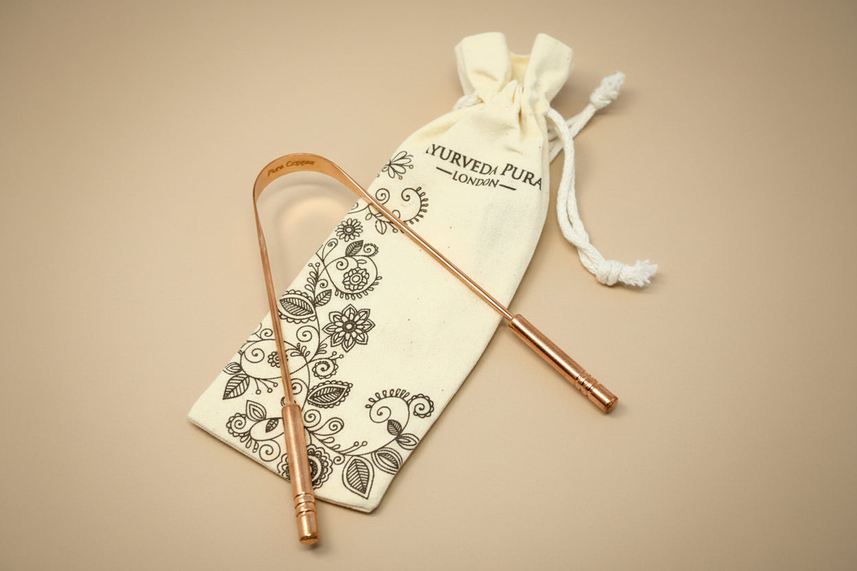 Copper tongue scraper with decorative pouch on a white background