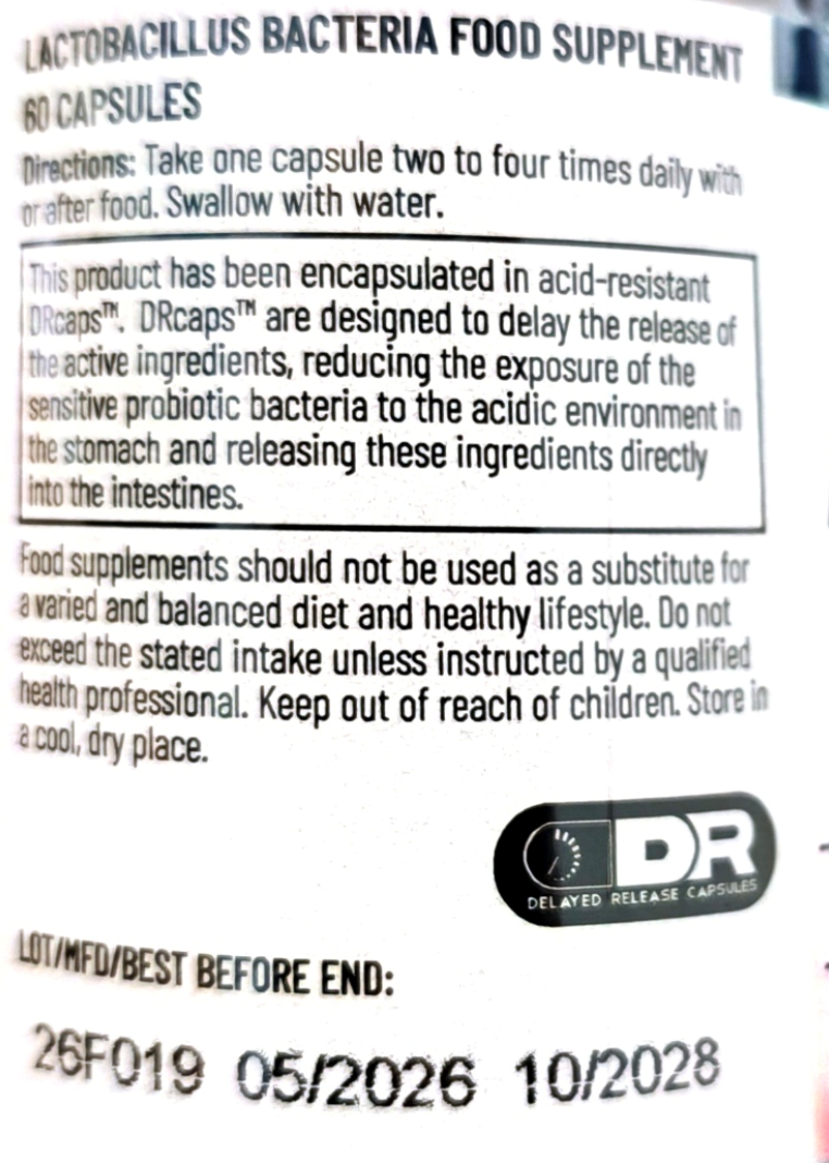 Close-up of a supplement label reading 'LACTOBACILLUS BACTERIA FOOD SUPPLEMENT 60 CAPSULES' with usage directions, a boxed product note about DRcaps delayed release capsules, and a DR logo seal.