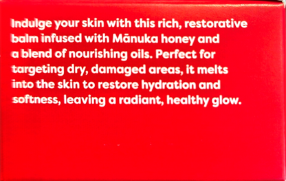 A close-up of a bright red box or package with white text describing a skin balm infused with Mánuka honey and nourishing oils.