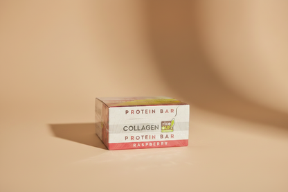 A hand holding a shrink-wrapped box of Collagen Protein Bar in Raspberry flavor. The packaging features a red and white design with a yellow and green Ice Dri logo, wrapped in clear plastic.