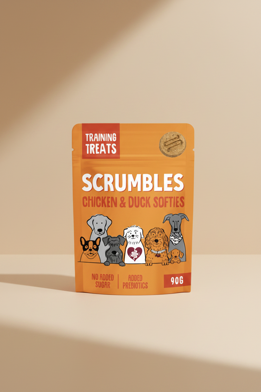 A 90g stand-up pouch of Scrumbles Training Treats for dogs, featuring Chicken & Duck Softies. The packaging is bright orange with a red banner reading 'TRAINING TREATS' and an illustration of six different dog breeds at the bottom.
