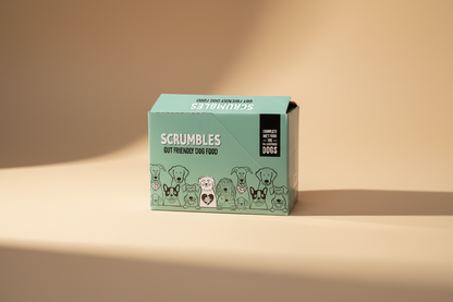 A mint green cardboard box of Scrumbles Gut Friendly Dog Food, featuring cartoon illustrations of various dog breeds along the bottom and a black label on the right side.