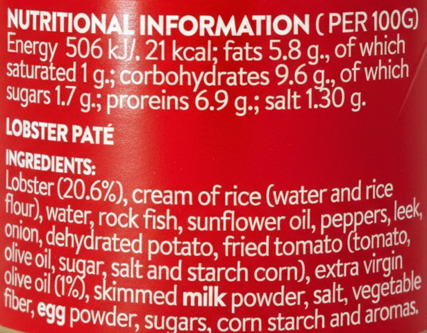 Close-up of a red cylindrical food package showing nutritional information and ingredients for lobster pate, with white text on a glossy red background.