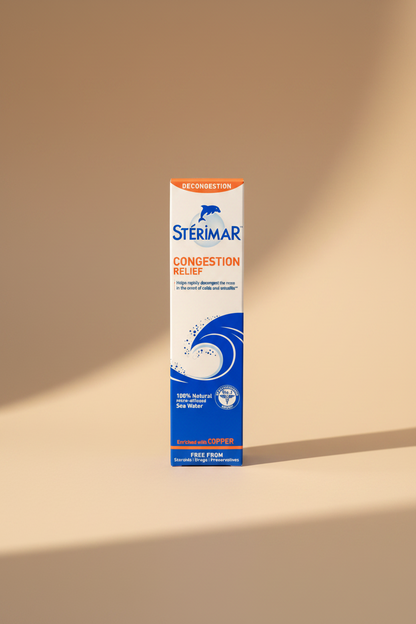 A hand holding a box of Stérimar Congestion Relief decongestion spray. The packaging is white with blue and orange text and graphics, including a dolphin logo and a wave illustration.