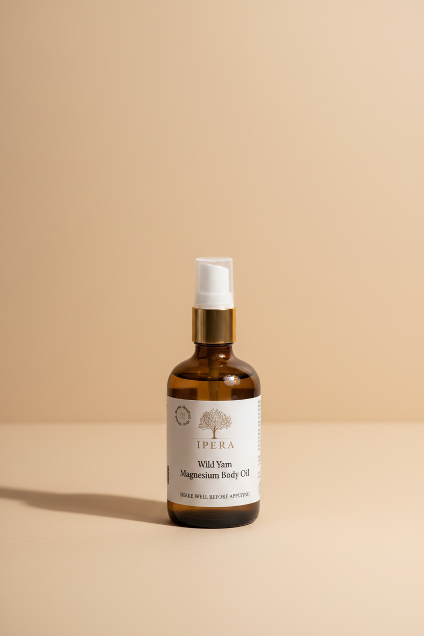 An amber glass spray bottle of Ipera Wild Yam Magnesium Body Oil with a white pump and a gold collar, on a white background.