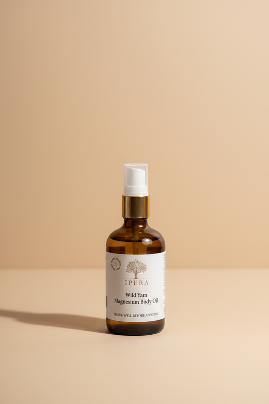 An amber glass spray bottle of Ipera Wild Yam Magnesium Body Oil with a white pump and a gold collar, on a white background.