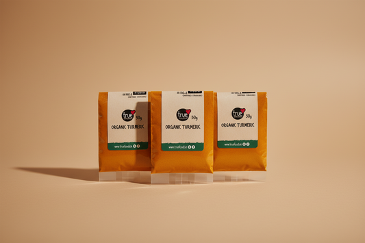 Three small packets of True Food Co. organic turmeric powder, 50g each, sealed in clear plastic packaging with white labels.