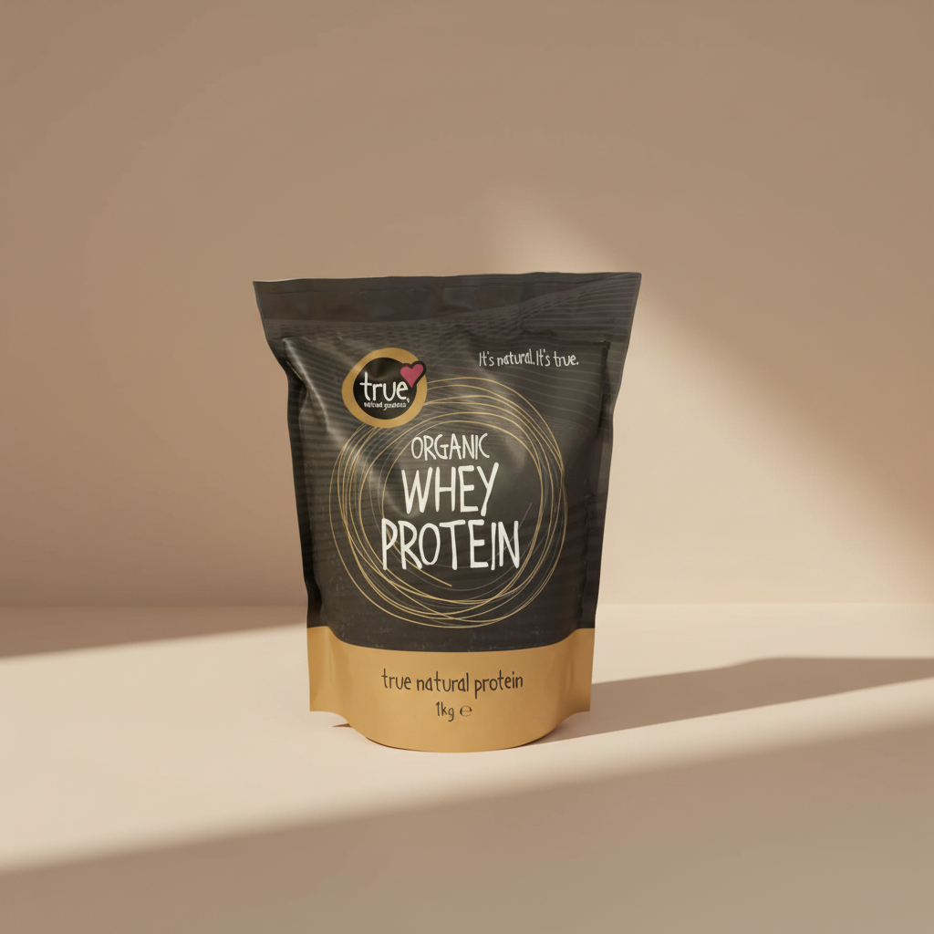 A 1kg stand-up pouch of True Organic Whey Protein on a plain white background. The packaging features a dark charcoal gray top half with gold circular line art and white text, and a light tan bottom half with black text.