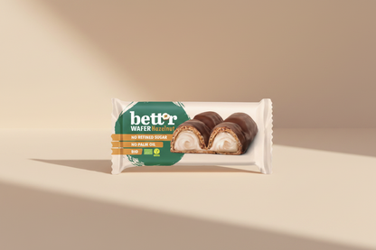 A packaged bar of Better Wafer Hazelnut on a plain white background. The wrapper is cream-colored with a large green logo area and an image of a sliced chocolate-covered wafer roll with a cream filling.