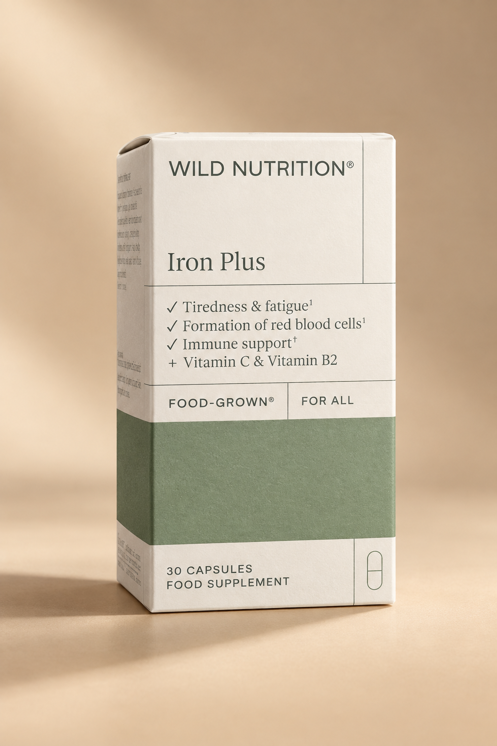 A hand holding a box of Wild Nutrition Iron Plus food supplement. The packaging is white with a sage green lower section and black text.