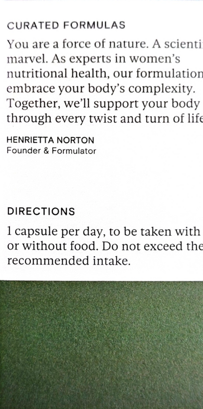 A close-up of a white printed card or label with black text, including the headline 'CURATED FORMULAS,' a quote attributed to Henrietta Norton, and dosage instructions. The lower portion shows a green textured surface.