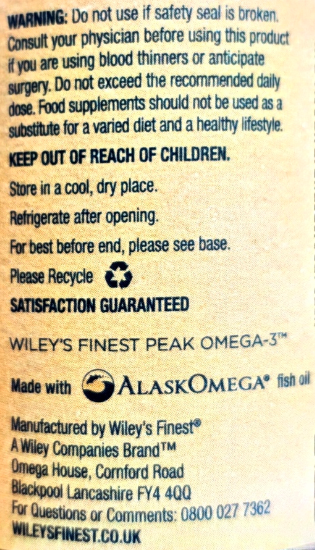 Back of a supplement package showing printed usage and recycling information in black text on a beige background, including warnings, storage instructions, and the Alaskan Omega fish oil branding.