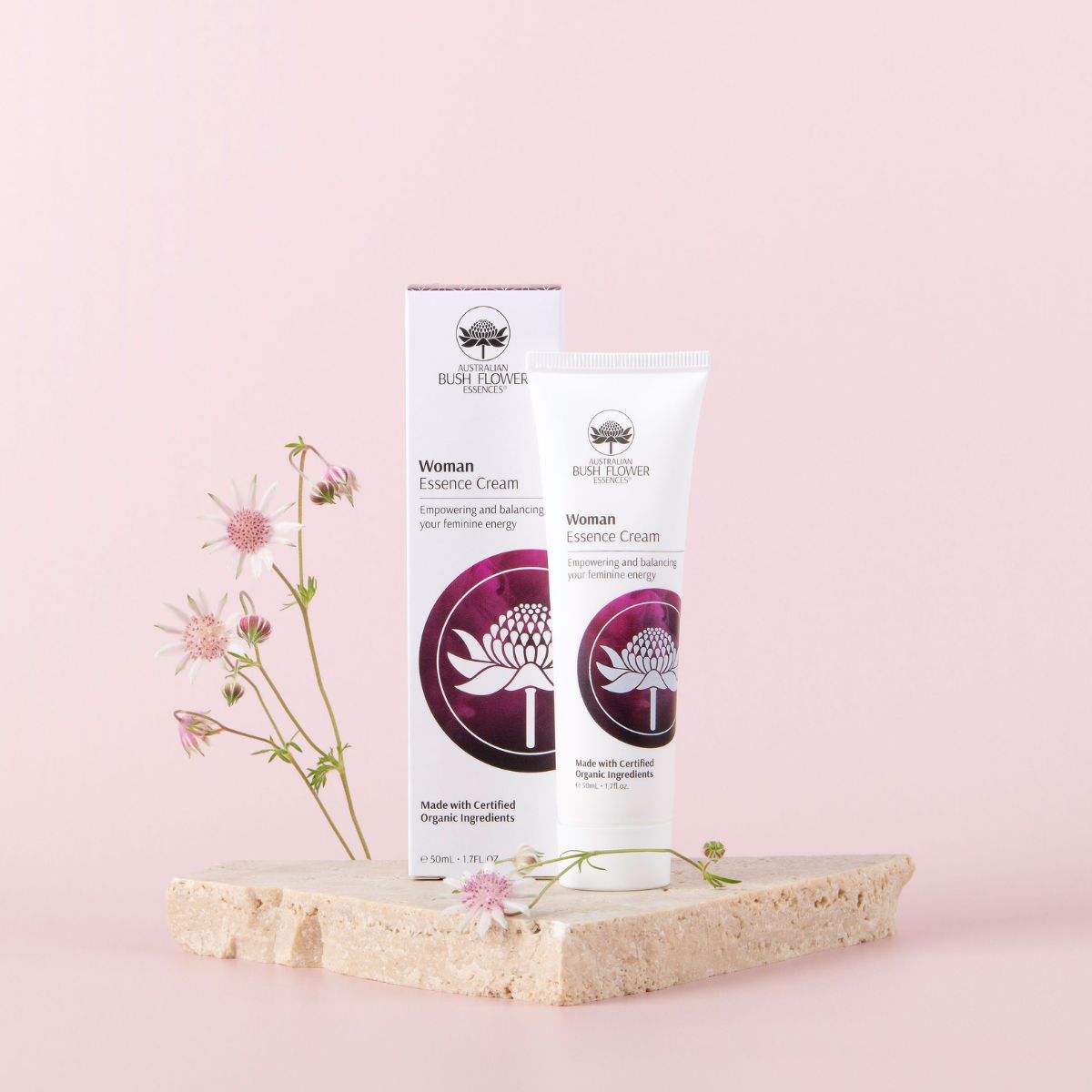 Woman Essence Cream 50ml displayed with flowers on a pink background