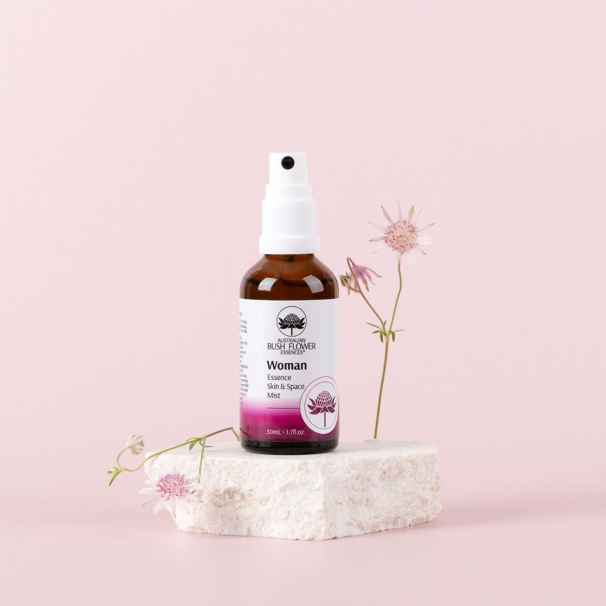 Woman Essence Skin and Space Mist 50ml displayed with flowers on a pink background